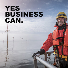 man with windmills at sea behind him